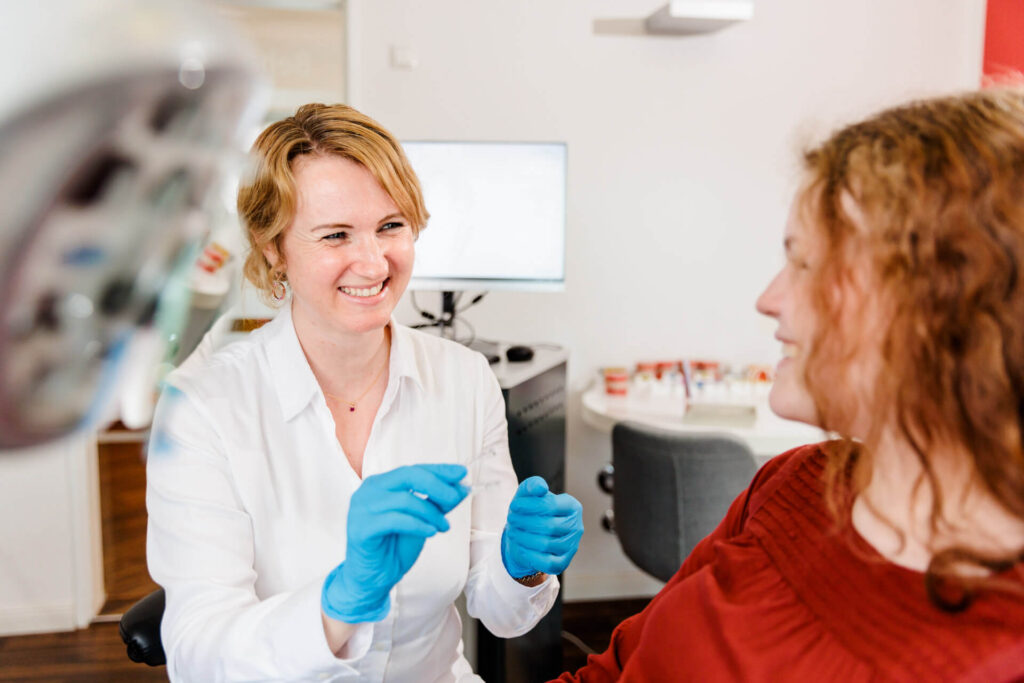 Foto von Frau Dr. Forster lächelnd mit blauen Handschuhen — Kieferorthopädie für Regensburg & Lappersdorf